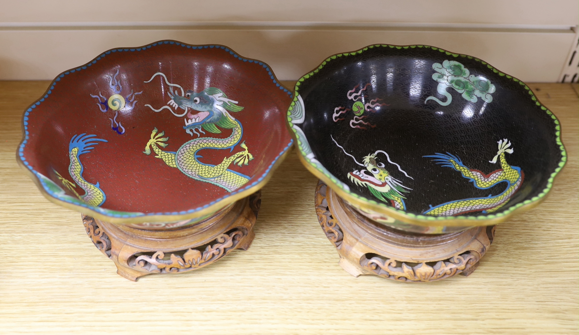 Two Chinese cloisonné enamel bowls on hardwood stands, enamelled with dragons chasing the flaming pearl together with three Star God figures, the largest 20cm in diameter